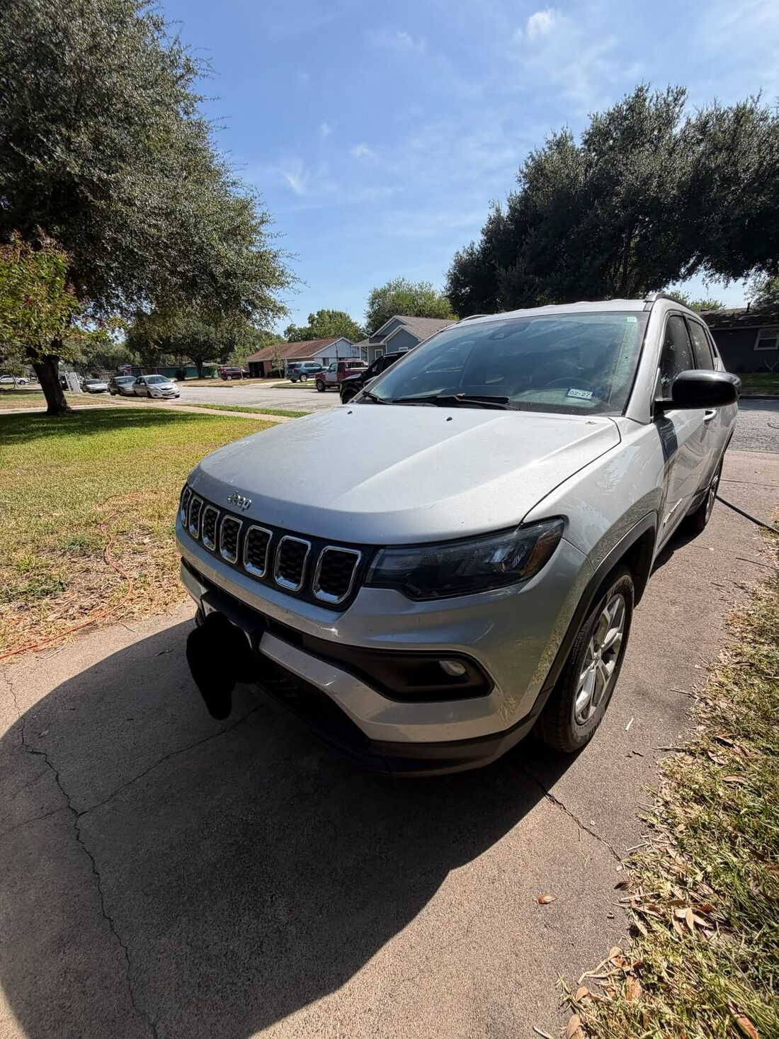 Silver Jeep Compass, freshly washed, in a driveway under a blue Texas sky